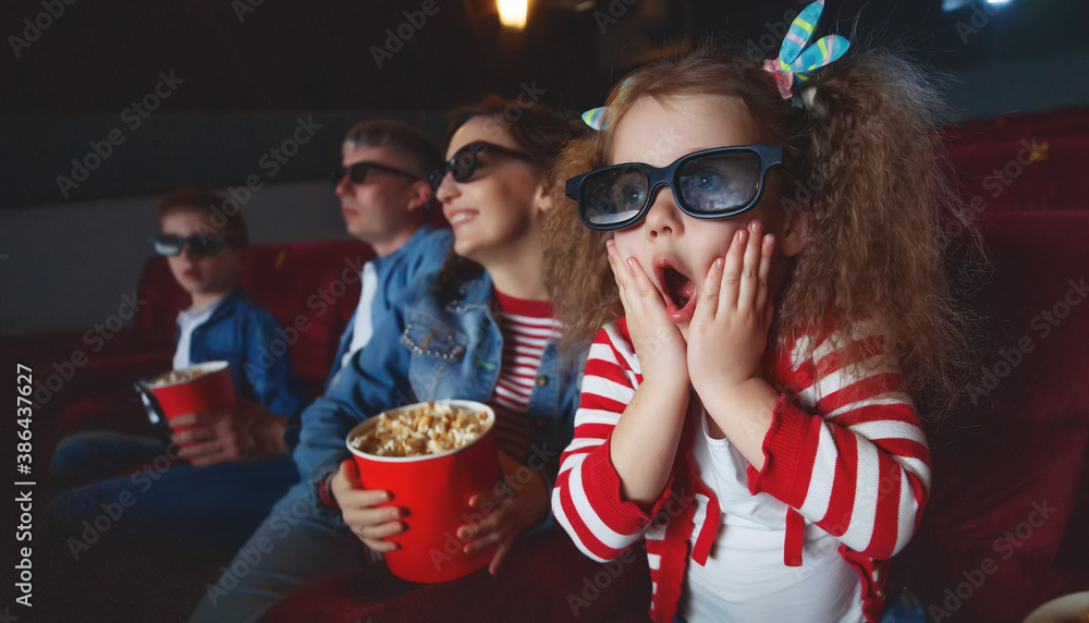 Family mom father and children are watching a projector, TV, cinema, movies with popcorn in the cinema. High quality photo. Family mom father and children are watching a projector, TV, cinema, movies with popcorn in the cinema. High quality photo.