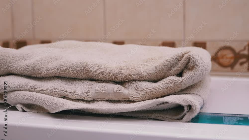 Close-up of hands putting stack of fresh white bath towels on the bed sheet. Room service maid cleaning hotel room macro closeup Close-up of hands putting stack of fresh white bath towels on the bed sheet. Room service maid cleaning hotel room macro closeup