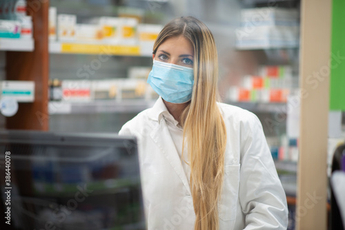 Smiling pharmacist wearing covid coronavirus mask in her pharmacy