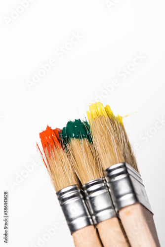 top view of paintbrushes with colorful paint on white background