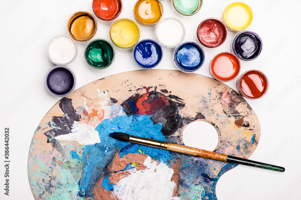 top view of palette with Gouache paints and paintbrush on white background