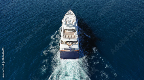 Aerial drone photo of luxury yacht with wooden deck cruising deep blue Aegean sea near island of Mykonos, Cyclades, Greece