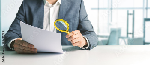 businessman or tax inspector analyzing document with magnifying glass in office. business financial audit concept. copy space photo