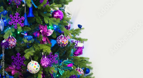Branches of christmas trees decorated with violet and blue decorations, garlands and toys. New Year concept, panoramic view, copy space. New year holiday or christmas background