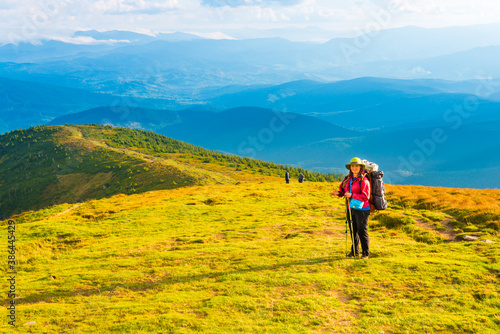 Happy traveling woman with backpack looking at mountain landscape