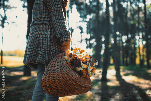 Close up of fashionable teenage girl holding basket of autumns flowers
