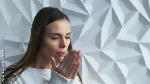 A beautiful brunette girl in white as a doctor coughs, sneezes, perhaps she is infected with covid, against a white volumetric background