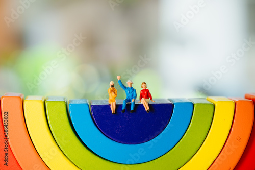 Miniature people, man and woman sitting on wooden rainbow using as business and social relationship concept