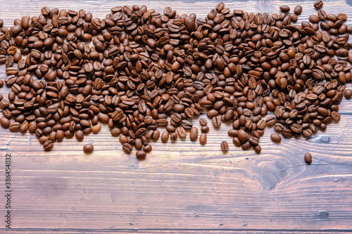 Roasted and aromatic Coffee beans on wooden table as background. Top view with and copy space for text. Macro photo of fresh arabica coffee beens