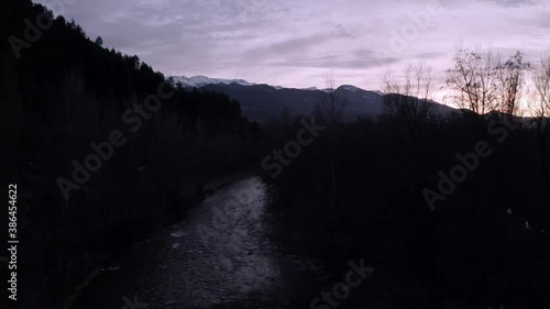 river flowing at dusk in front of snowy mountains