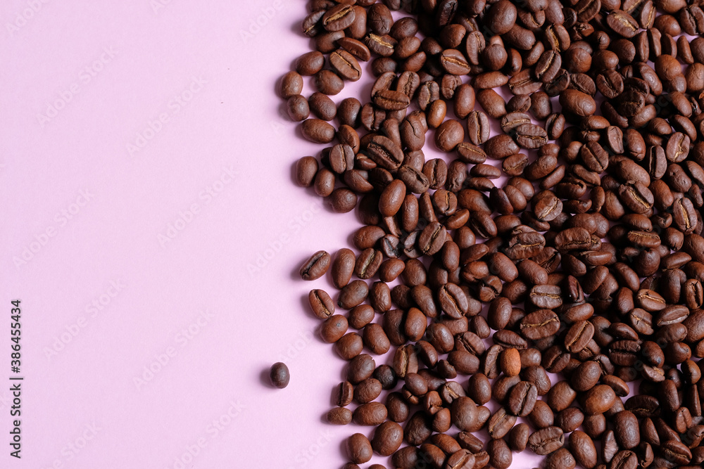 Fototapeta premium Roasted and aromatic Coffee beans on pink colored surface as background. Top view with and copy space for text. Macro photo of fresh arabica coffee beens.