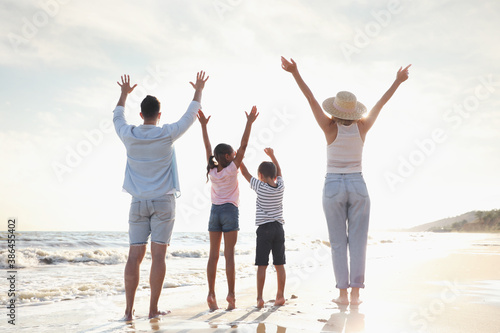 Family on sandy beach near sea, back view. Summer vacation
