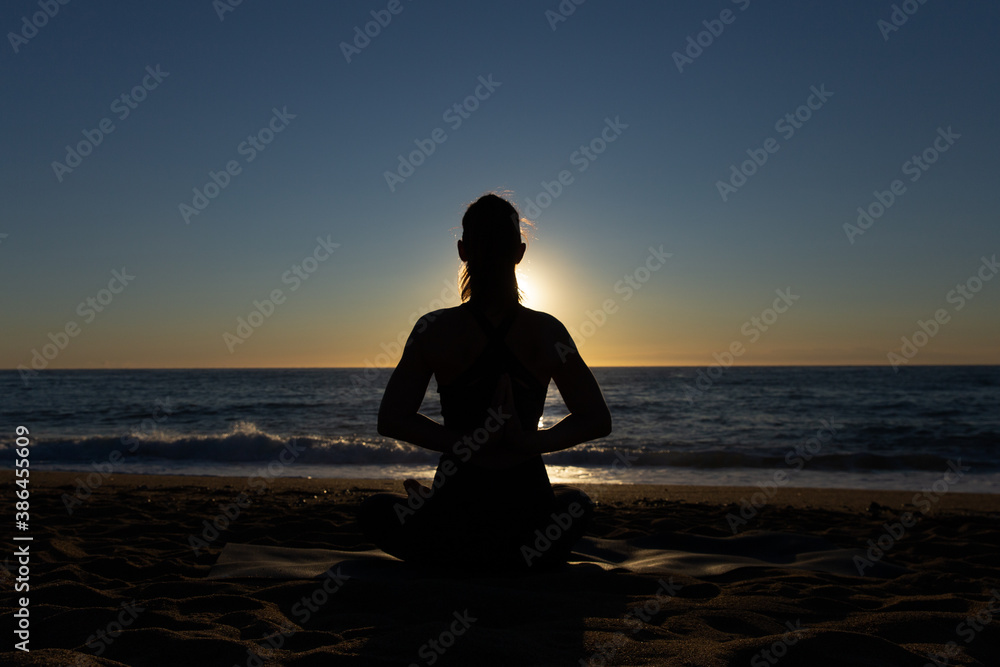 Caucasian woman doing stretching and yoga on Barceloneta beach in Barcelona
