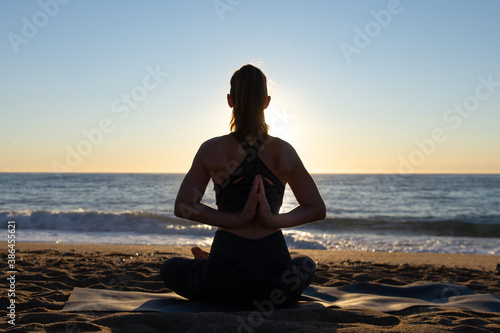 Caucasian woman doing stretching and yoga on Barceloneta beach in Barcelona 