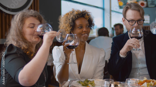 Diverse business partners clinking glasses celebrating agreement in restaurant
