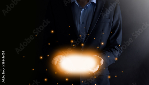 Businness man holding hands open with glowing lights on dark background