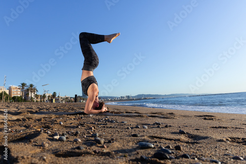 Caucasian woman doing stretching and yoga on Barceloneta beach in Barcelona
 photo