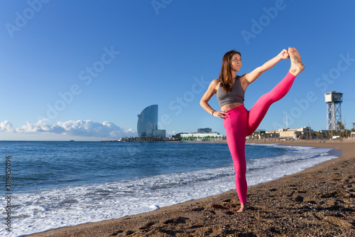 Caucasian woman doing stretching and yoga on Barceloneta beach in Barcelona photo