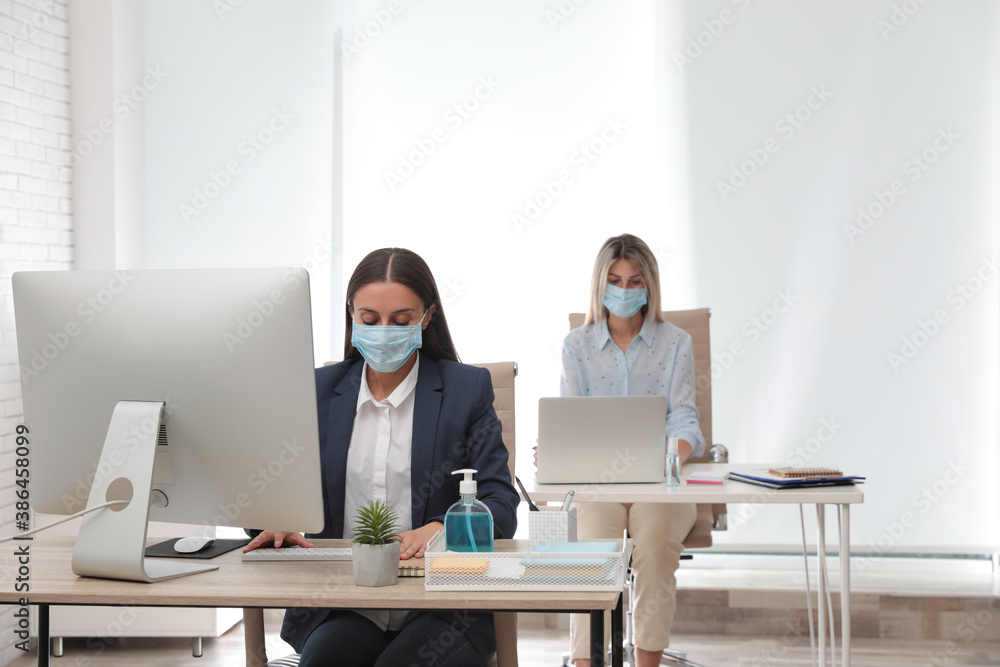 Office employees in respiratory masks at workplace Office employees in respiratory masks at workplace