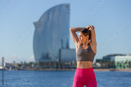 Caucasian woman doing stretching and yoga on Barceloneta beach in Barcelona photo