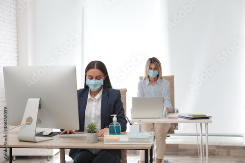 Office employees in respiratory masks at workplace