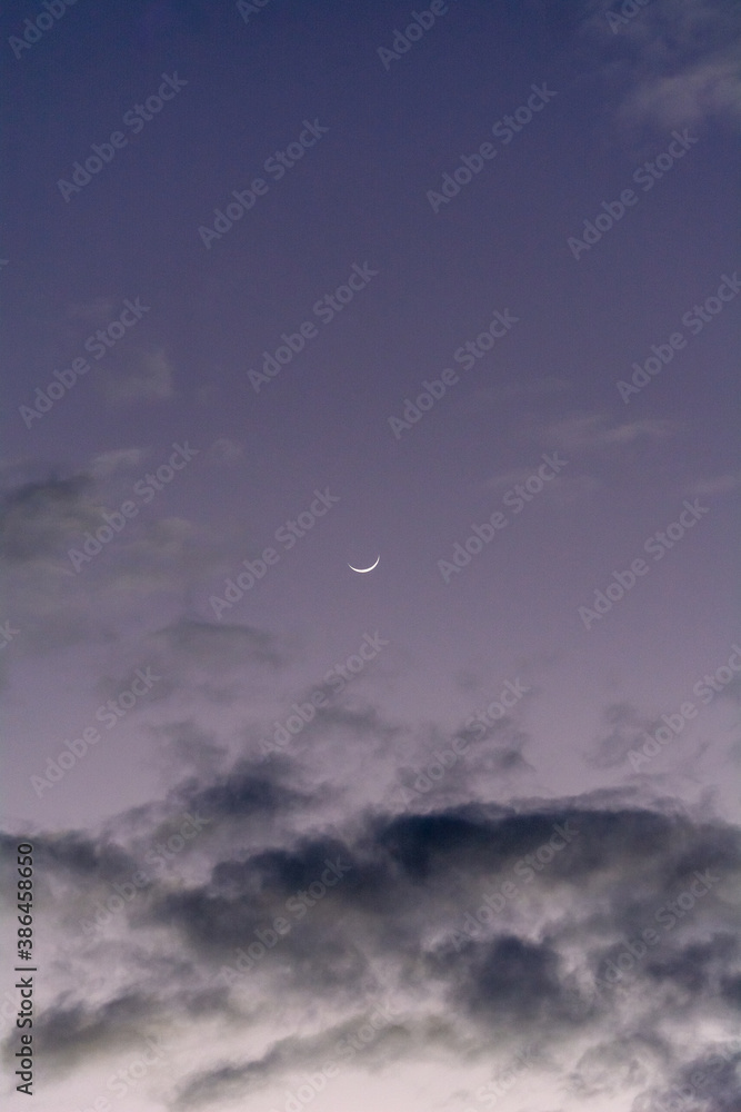 crescent moon in the sky with clouds in a dark sunset crescent moon in the sky with clouds in a dark sunset