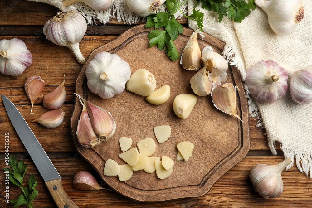 Flat lay composition with fresh sliced and whole garlic on wooden table. Organic product Flat lay composition with fresh sliced and whole garlic on wooden table. Organic product