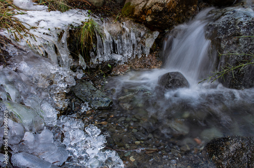 Tiny waterfall in the mountains surrounded by frozen stalactites during winter season in Esquel, Patagonia, Argentina