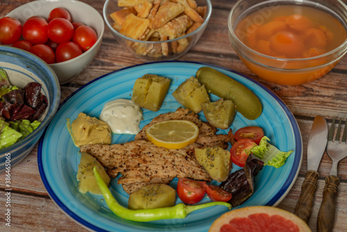 Vegetable fruit yoghurt apricot courgette chicken on blue plate and wooden table