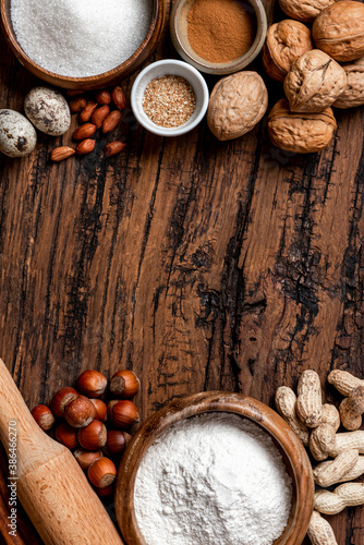 Ingredients for making a sweet pie or cookies with nuts on a old wooden table top view. Free space for text. Various nuts, flour, sugar, eggs and cinnamon flat lay. Food background. Copy space.