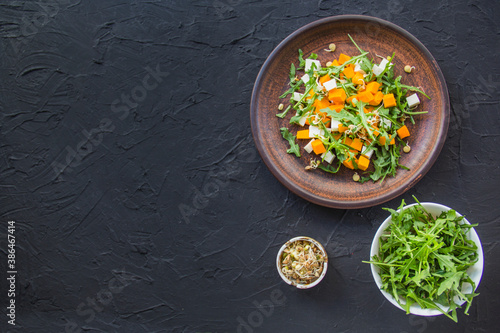 Delicious healthy pumpkin salad with arugula and cheese. Creative atmospheric decoration