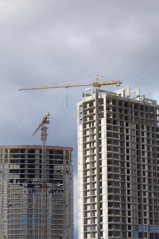 Construction of modern multi-storey buildings. New development of a residential area. House frames and construction cranes at the construction site.