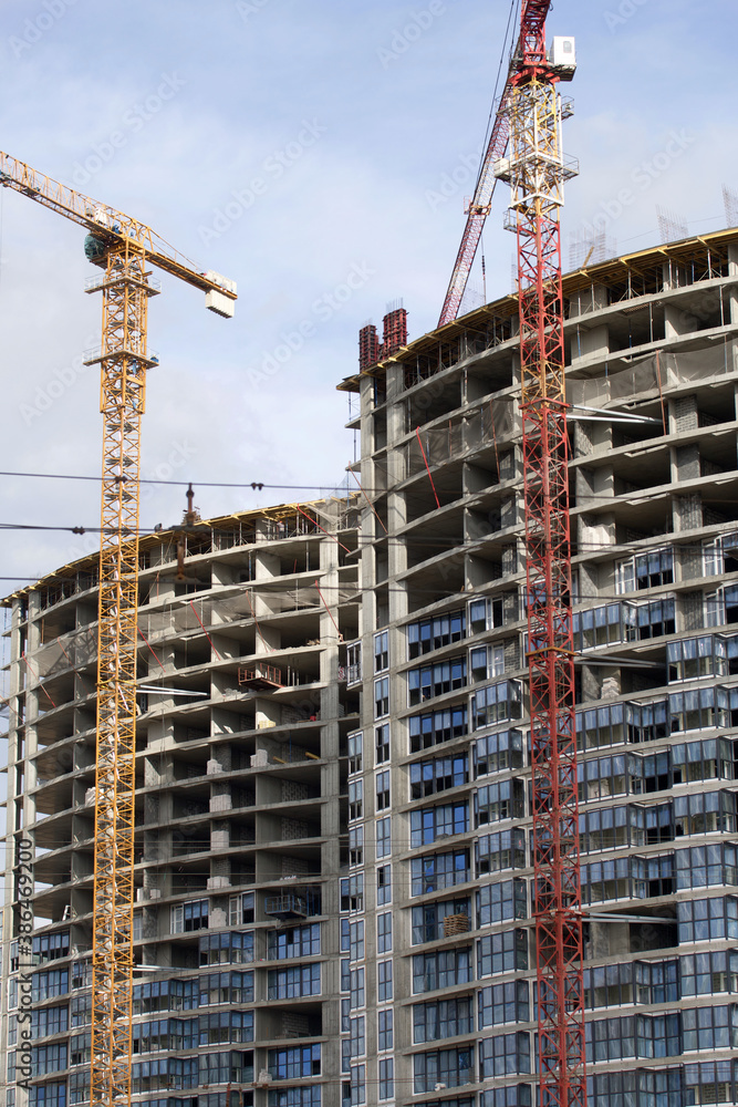 Construction of modern multi-storey buildings. New development of a residential area. House frames and construction cranes at the construction site. Construction of modern multi-storey buildings. New development of a residential area. House frames and construction cranes at the construction site.