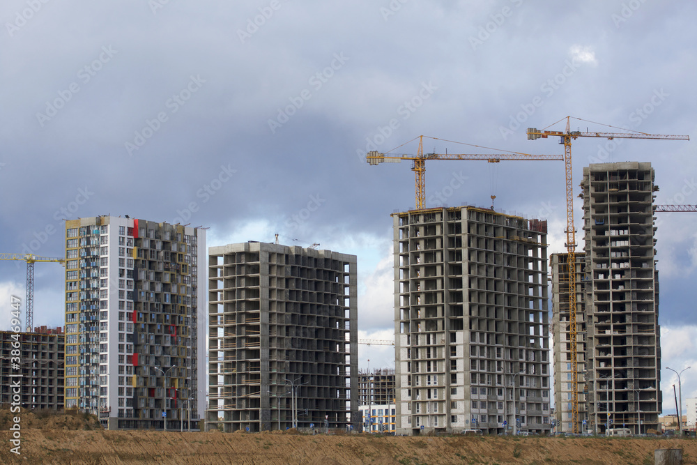 Construction of modern multi-storey buildings. New development of a residential area. House frames, construction cranes and building materials at the construction site. Construction of modern multi-storey buildings. New development of a residential area. House frames, construction cranes and building materials at the construction site.