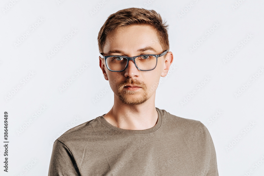 Young handsome man with glasses a brunette beard. Student, worker, businessman posing for photo isolated on gray background. Place for advertising. Young handsome man with glasses a brunette beard. Student, worker, businessman posing for photo isolated on gray background. Place for advertising.