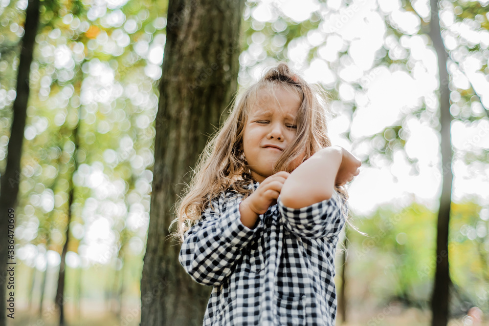 A cute little girl crying in the autumn park. mosquito bite, mite, allergy, irritation, itching. A cute little girl crying in the autumn park. mosquito bite, mite, allergy, irritation, itching.