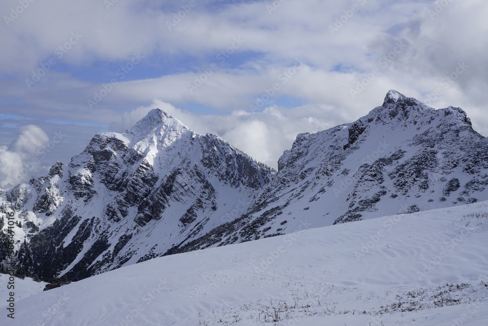 Aussicht auf die österreichischen Alpen mit Schnee im Sonnenlicht und Wolken