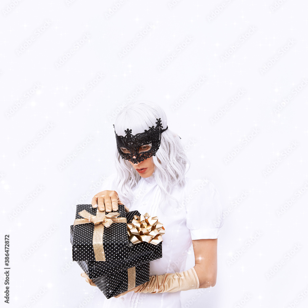 Fashion Magic Lady in mask on white background space holds winter present box. Minimal fashion festive Christmas / New Year, holidays, birthday party, celebration concept. Fashion Magic Lady in mask on white background space holds winter present box. Minimal fashion festive Christmas / New Year, holidays, birthday party, celebration concept.
