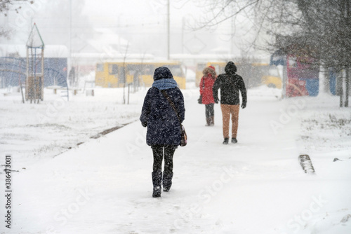 Pedestrians make their way through the blizzard in the city. Selective focus.