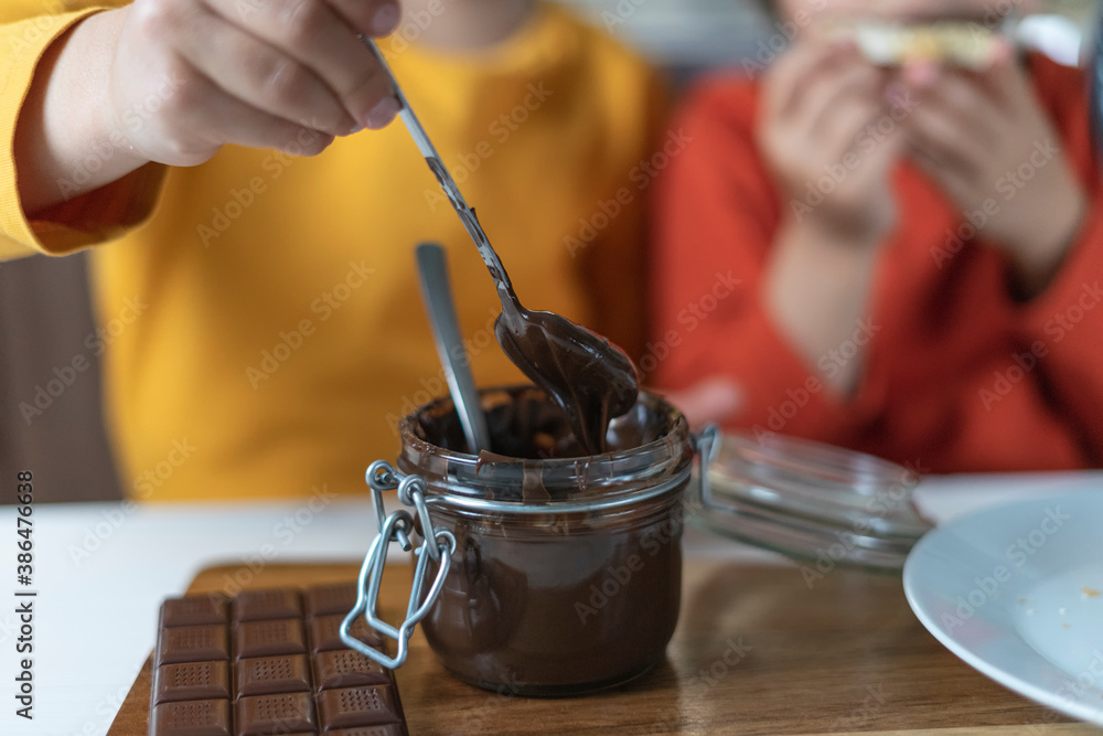 Children spread chocolate paste on toast bread in the kitchen background. Breakfast happy family having fun with food Children spread chocolate paste on toast bread in the kitchen background. Breakfast happy family having fun with food
