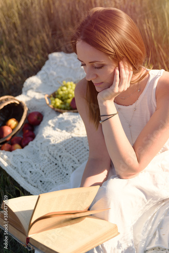 beautiful girl reads a book in nature, self-development, 
at sunset, the rays of the sun in your hair