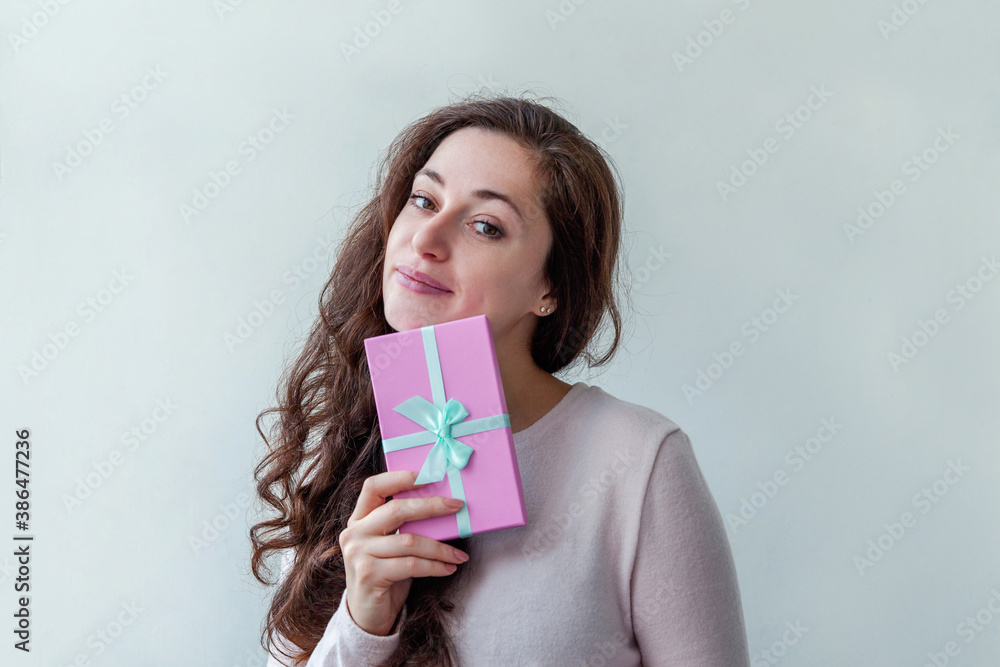 Young positive woman holding small pink gift box isolated on white background. Preparation for holiday. Girl looking happy and excited. Christmas birthday valentine celebration present concept. Young positive woman holding small pink gift box isolated on white background. Preparation for holiday. Girl looking happy and excited. Christmas birthday valentine celebration present concept.