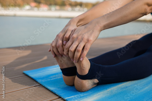 close-up of hands holding feet on a blue yoga Mat