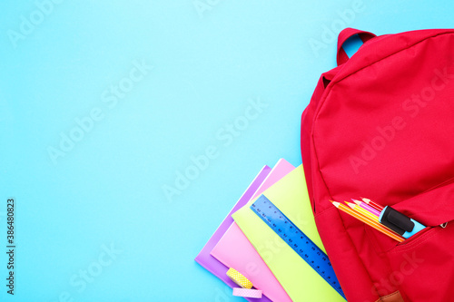Backpack with school supplies on blue background