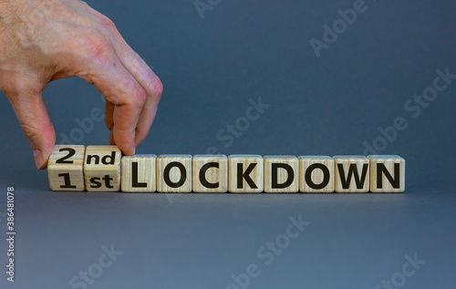 Symbol for a second lockdown. Hand turns cubes and changes the expression '1st lockdown' to '2nd lockdown'. Beautiful grey background. Medical and covid-19 pandemic concept, copy space. photo