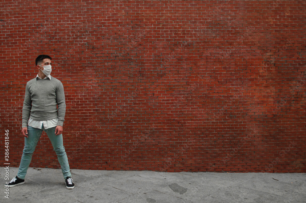 Un joven atlético posando delante de una pared con una mascarilla sanitaria-concepto de la nueva normalidad