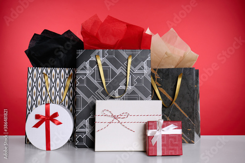 Shopping paper bags and gift boxes on red background photo