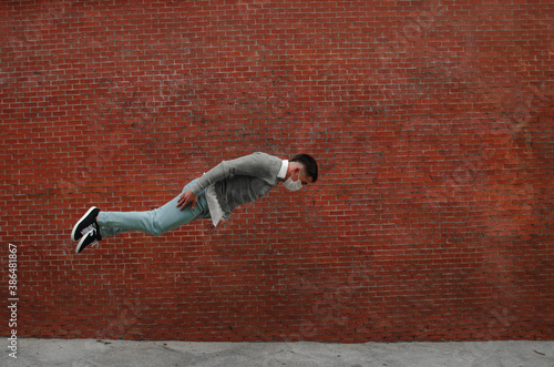 Un joven atlético haciendo un salto con una mascarilla sanitaria-concepto de la nueva normalidad