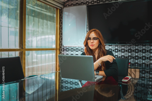 Mujer joven mexicana latina trabajando en oficina de empresa computadora portatil feliz alegre maestra directora photo