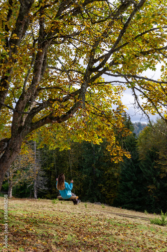 Girl on a swing in the autumn mountains